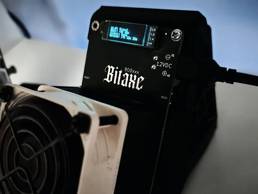 A Bitaxe in its case, screen lit